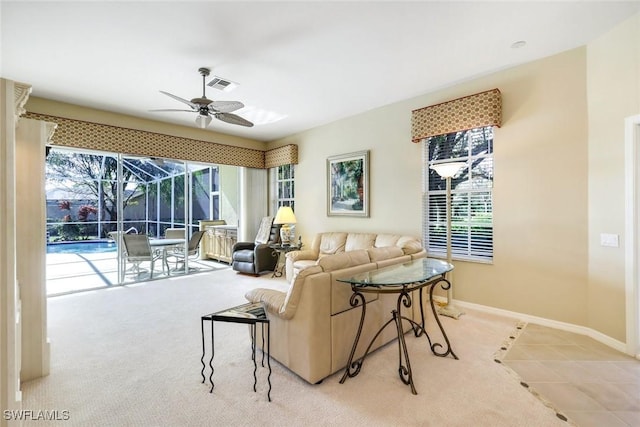 living room featuring visible vents, a ceiling fan, a sunroom, light carpet, and baseboards