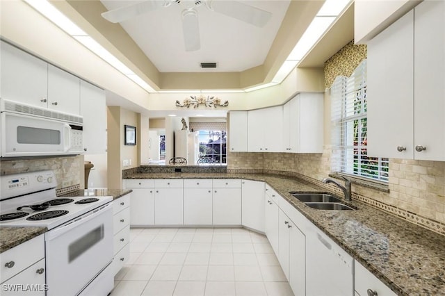 kitchen with white appliances, visible vents, dark stone counters, and a sink