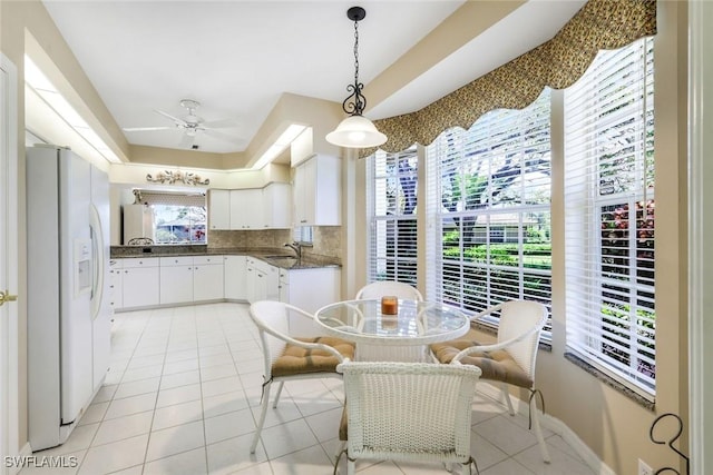 kitchen featuring dark countertops, light tile patterned floors, tasteful backsplash, and white fridge with ice dispenser