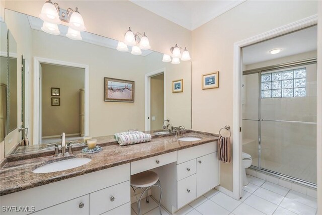 bathroom featuring toilet, a stall shower, double vanity, and a sink