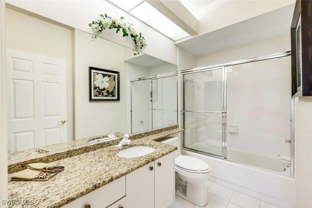 bathroom with tile patterned flooring, shower / bath combination with glass door, vanity, and toilet