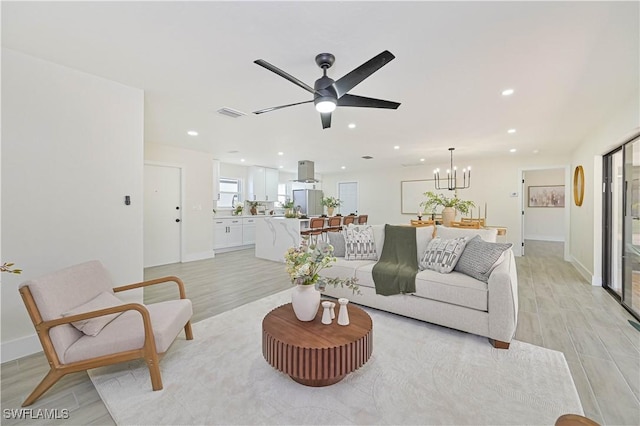 living area with recessed lighting, ceiling fan with notable chandelier, visible vents, baseboards, and light wood-style floors