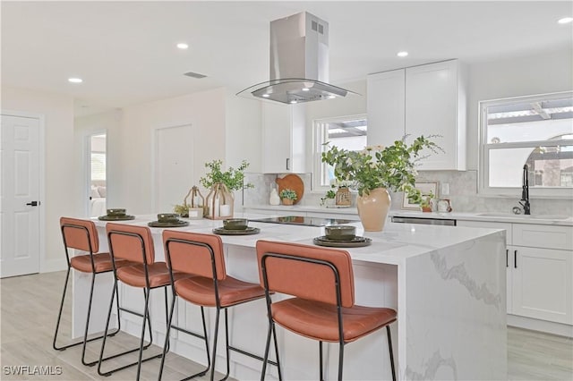 kitchen featuring a center island, white cabinetry, a sink, and island range hood