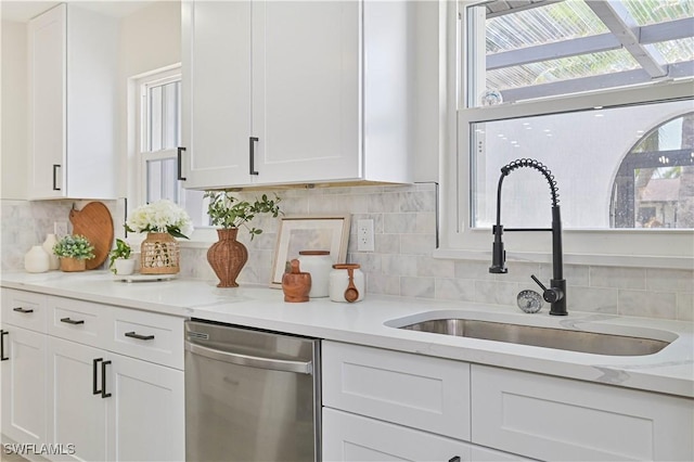 kitchen featuring plenty of natural light, white cabinetry, dishwasher, and a sink