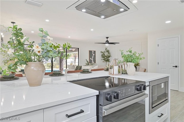 kitchen featuring light stone counters, range with electric cooktop, white cabinetry, visible vents, and built in microwave