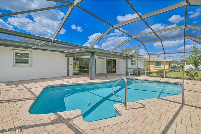 outdoor pool featuring a lanai, a patio area, and ceiling fan