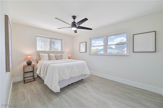 bedroom featuring light wood finished floors, a ceiling fan, and baseboards