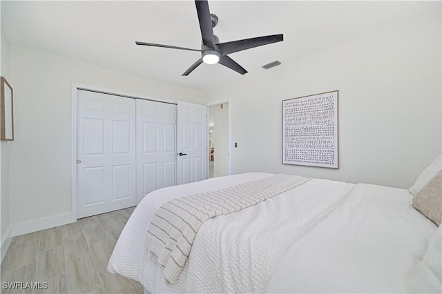 bedroom with light wood finished floors, a closet, visible vents, ceiling fan, and baseboards