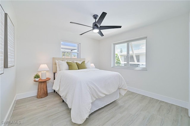 bedroom featuring light wood finished floors, multiple windows, and baseboards