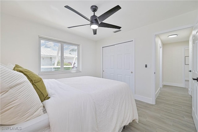 bedroom with light wood-style flooring, visible vents, a ceiling fan, baseboards, and a closet