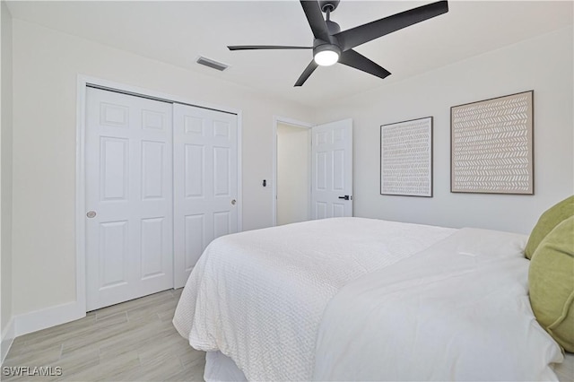 bedroom with ceiling fan, visible vents, baseboards, light wood-style floors, and a closet