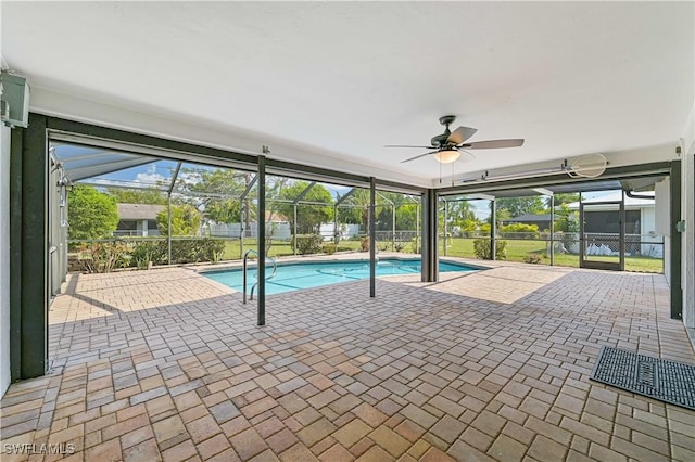 outdoor pool featuring glass enclosure, ceiling fan, and a patio