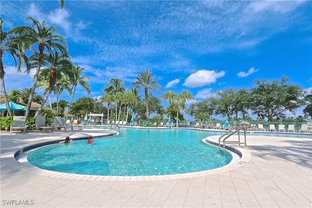 community pool with a patio area and fence