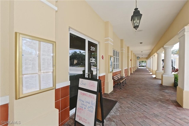 hallway featuring brick floor and ornate columns