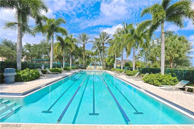 community pool with a patio area and fence