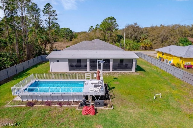 rear view of house with a sunroom, a fenced backyard, a fenced in pool, and a yard