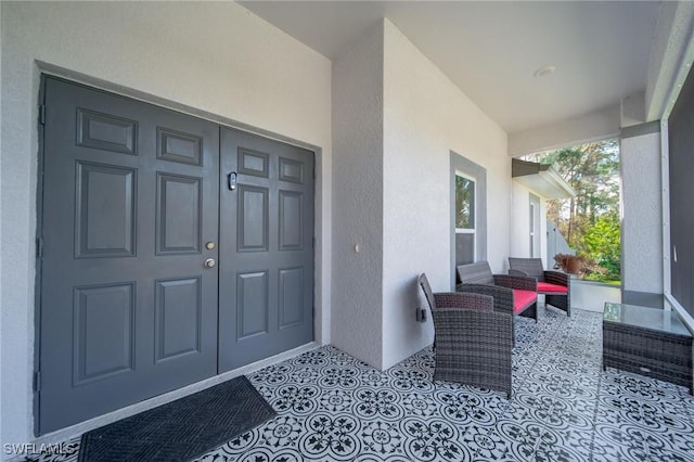 doorway to property with covered porch and stucco siding