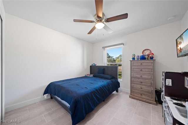 bedroom with a ceiling fan, baseboards, and light tile patterned floors