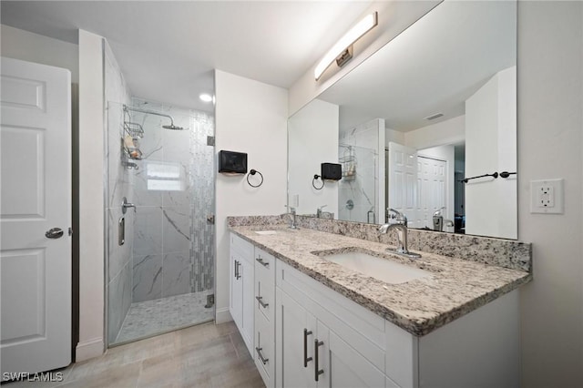 full bathroom with visible vents, double vanity, a sink, and a marble finish shower