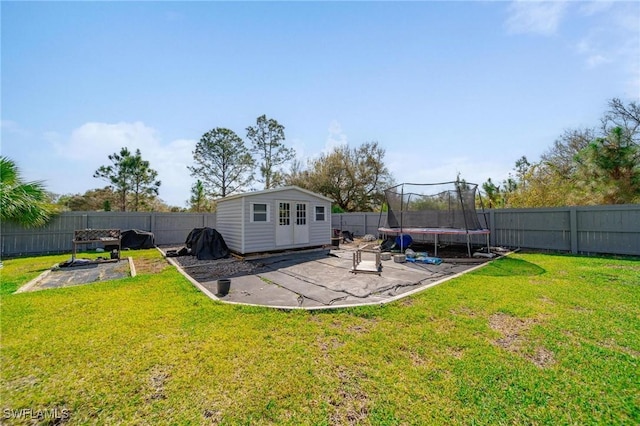 view of yard featuring a fenced backyard, a trampoline, a patio, and an outbuilding