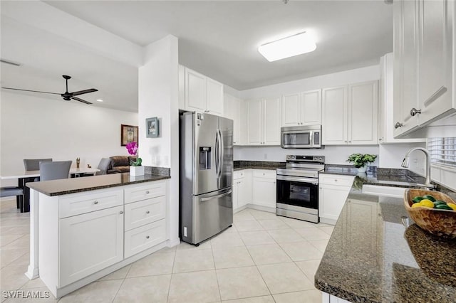 18911 Bay Woods Lake Dr Unit 101, Fort Myers, FL 33908 - kitchen with stainless steel appliances, a peninsula, a sink, dark stone counters, and light tile patterned flooring