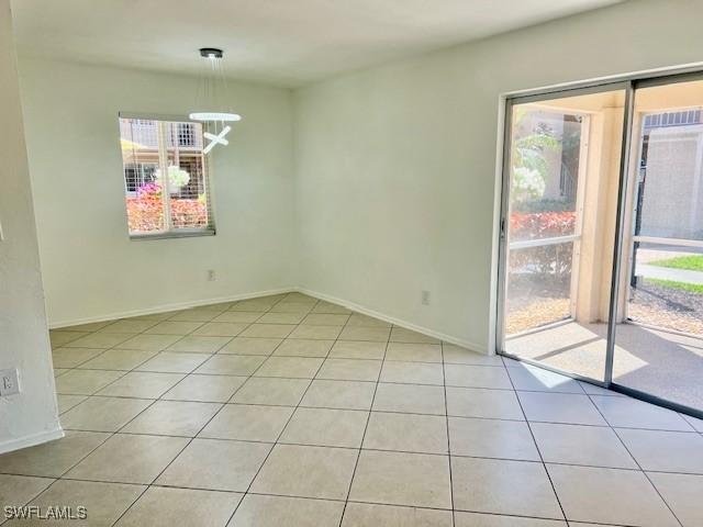 unfurnished room featuring a chandelier, baseboards, and light tile patterned floors