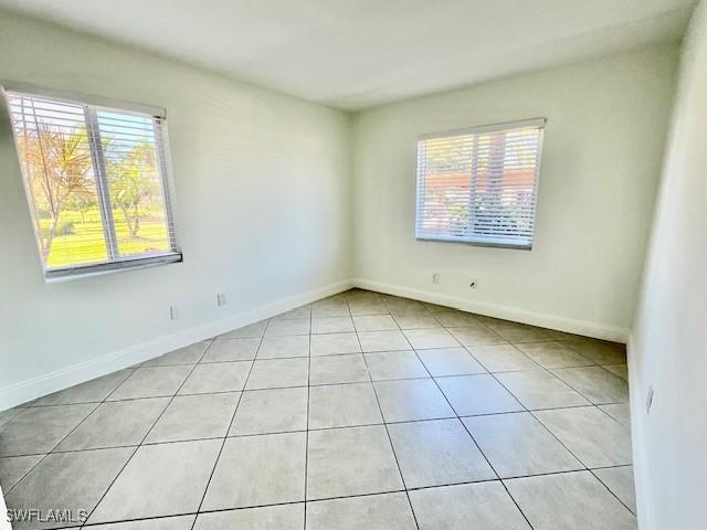 spare room with light tile patterned flooring and baseboards