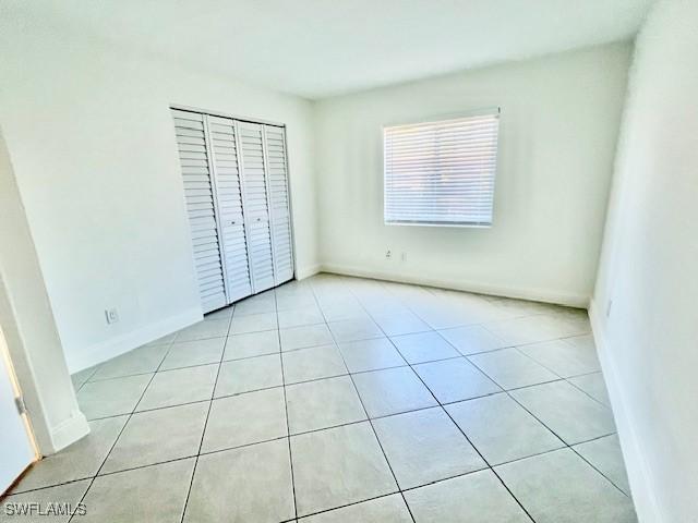 unfurnished bedroom with a closet, baseboards, and light tile patterned floors