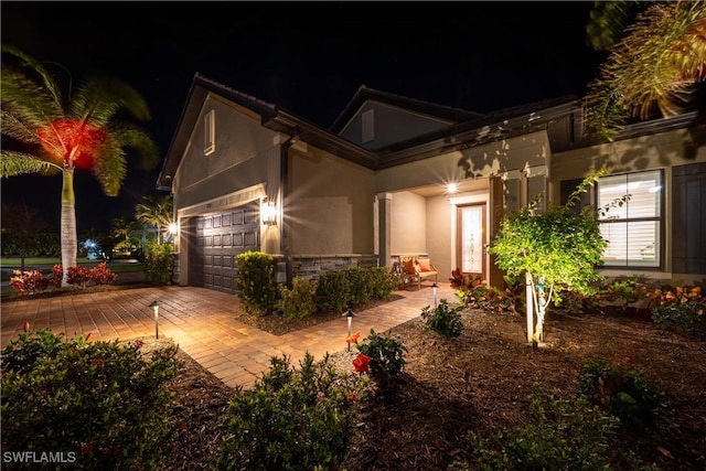 view of front of home with an attached garage, stone siding, and stucco siding