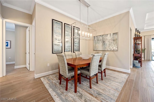 dining room with wood tiled floor, a notable chandelier, crown molding, and baseboards