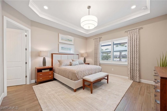 bedroom featuring light wood-type flooring, baseboards, a tray ceiling, and ornamental molding