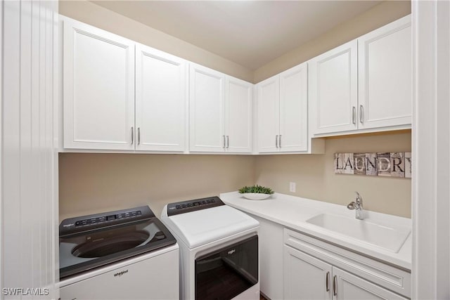 clothes washing area with a sink, cabinet space, and washer and dryer