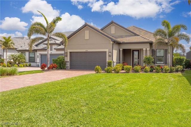 view of front of home featuring decorative driveway, stucco siding, an attached garage, a tiled roof, and a front lawn