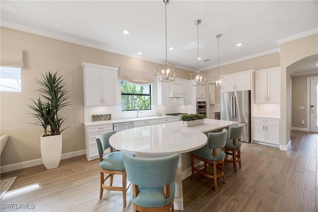 dining space featuring arched walkways, ornamental molding, light wood-type flooring, and baseboards