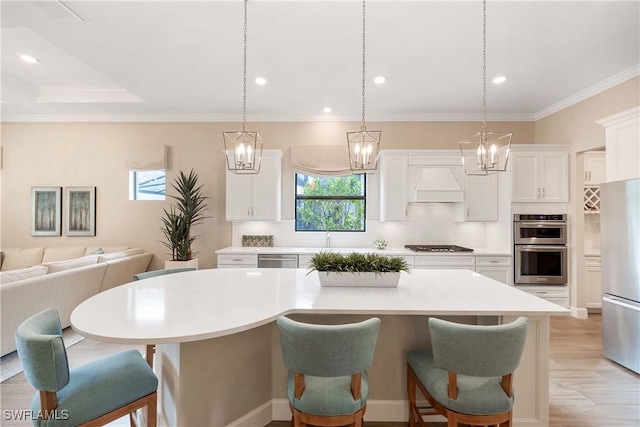 kitchen featuring custom exhaust hood, light wood-style flooring, backsplash, appliances with stainless steel finishes, and a kitchen breakfast bar