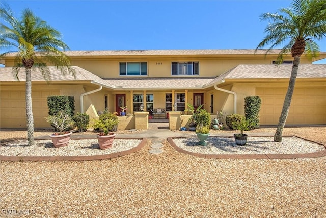 view of front of property with an attached garage, a shingled roof, and stucco siding