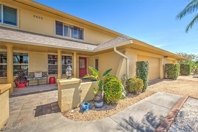 property entrance with an attached garage, a shingled roof, and stucco siding