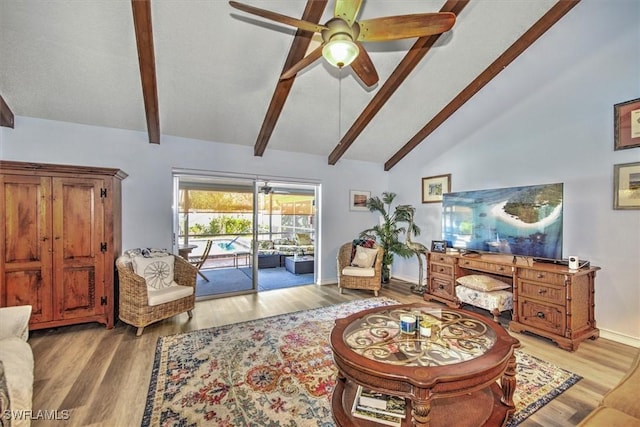 living room with lofted ceiling with beams, baseboards, a ceiling fan, and wood finished floors