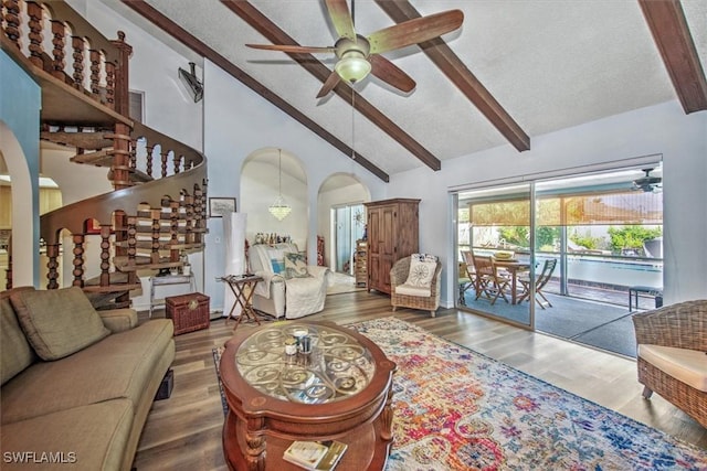 living area featuring arched walkways, beam ceiling, a ceiling fan, wood finished floors, and high vaulted ceiling