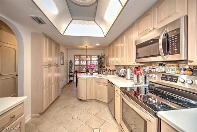 kitchen featuring light countertops, visible vents, light brown cabinetry, appliances with stainless steel finishes, and a peninsula