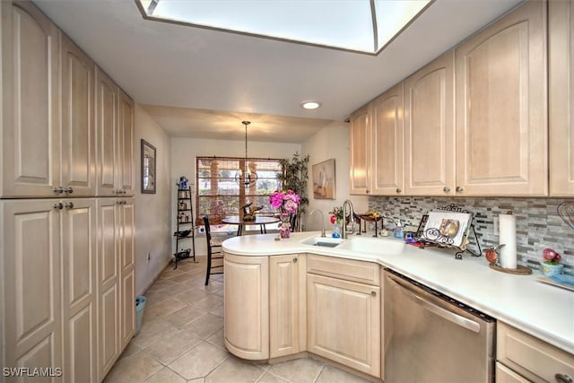 kitchen with backsplash, a peninsula, light countertops, stainless steel dishwasher, and a sink