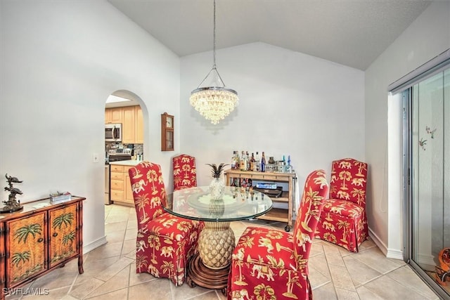 dining space featuring vaulted ceiling, light tile patterned floors, arched walkways, and a notable chandelier