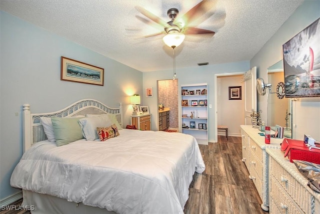 bedroom with dark wood-style floors, visible vents, a textured ceiling, and a ceiling fan