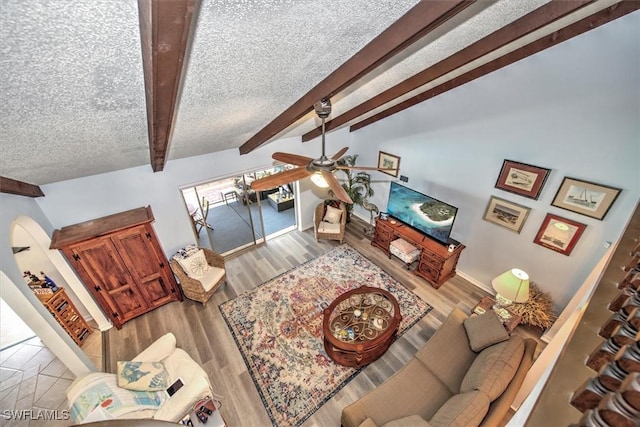 living room with lofted ceiling with beams, ceiling fan, a textured ceiling, wood finished floors, and baseboards