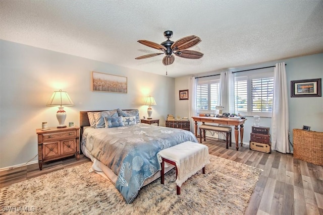 bedroom featuring a textured ceiling, ceiling fan, wood finished floors, and baseboards