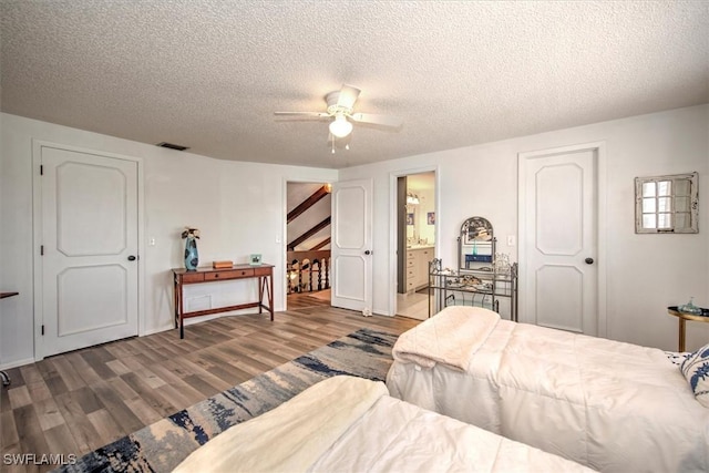 bedroom with a ceiling fan, visible vents, a textured ceiling, and wood finished floors