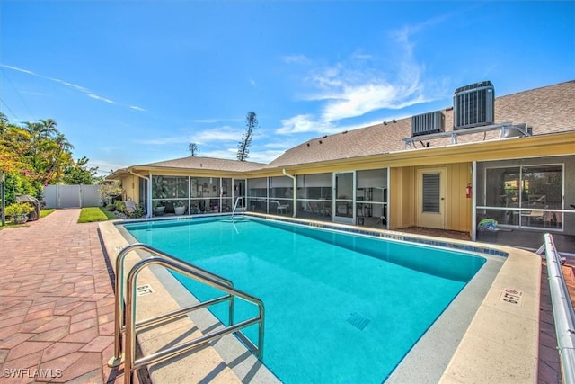 view of swimming pool featuring a patio, central AC, fence, a sunroom, and a fenced in pool