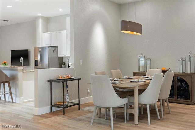 dining room with baseboards, light wood-style flooring, and recessed lighting