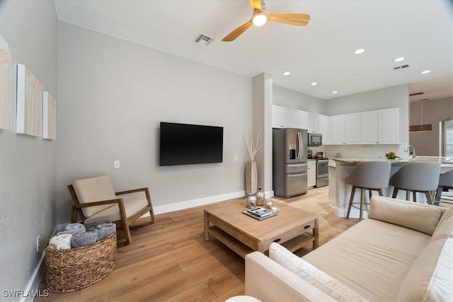 living room featuring ceiling fan, recessed lighting, visible vents, baseboards, and light wood-type flooring