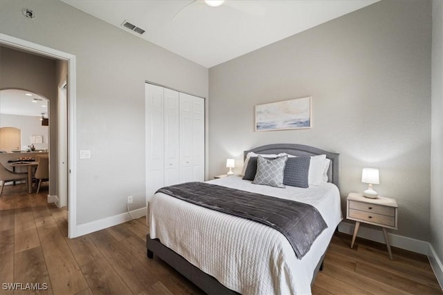 bedroom with arched walkways, a closet, visible vents, and hardwood / wood-style floors